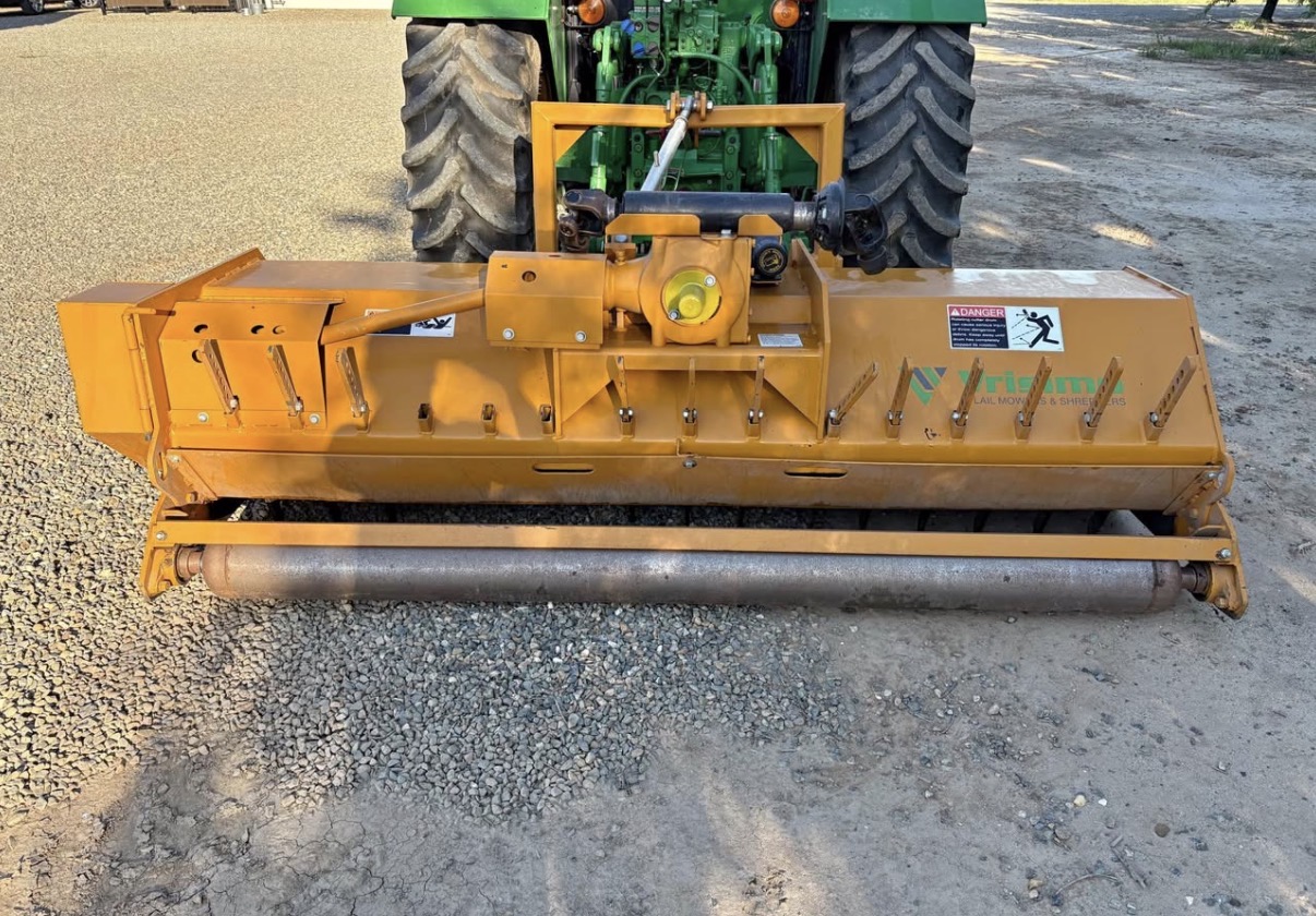 Flail mower attached to a tractor for orchard maintenance